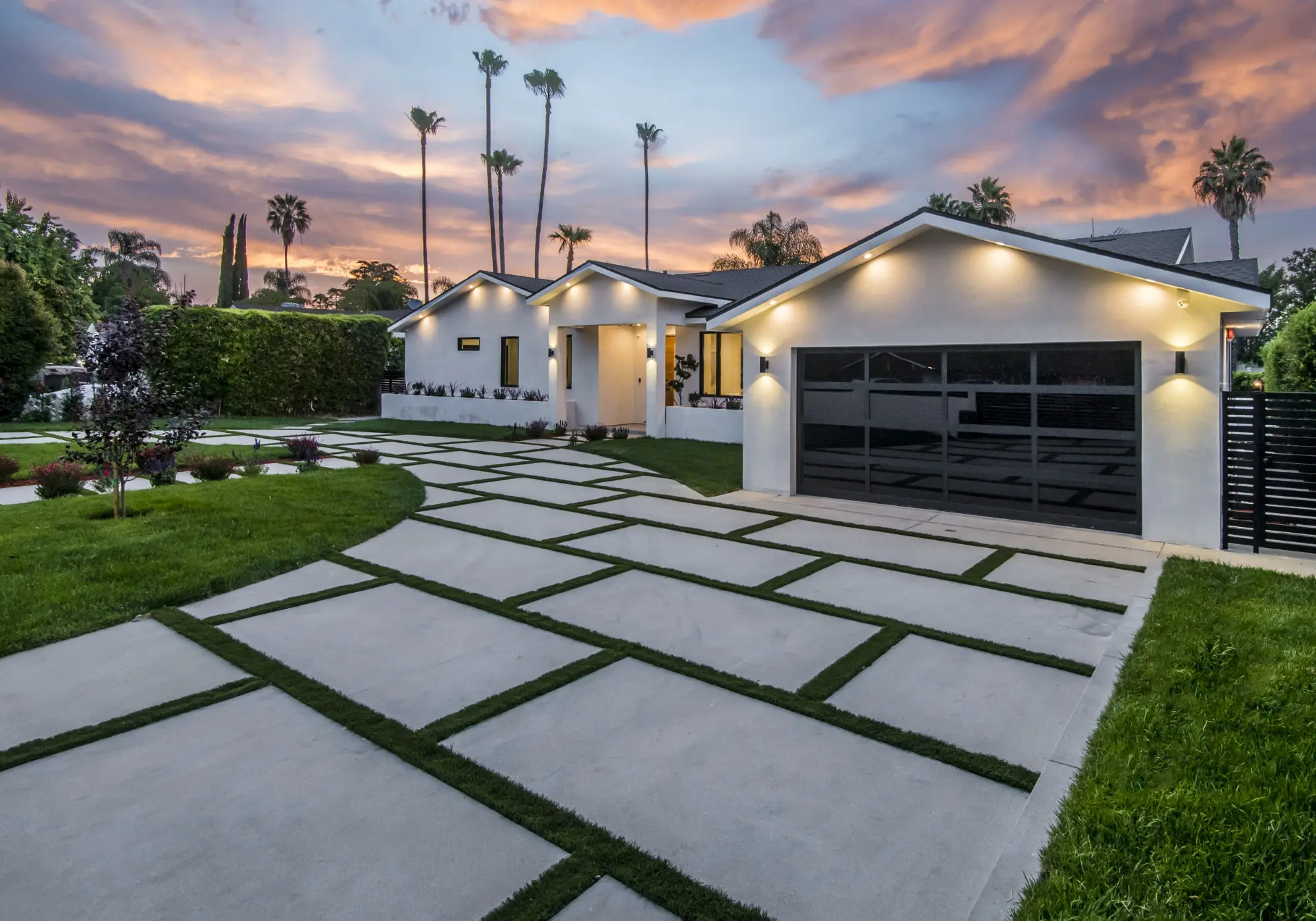 Modern house with landscaped driveway at sunset.