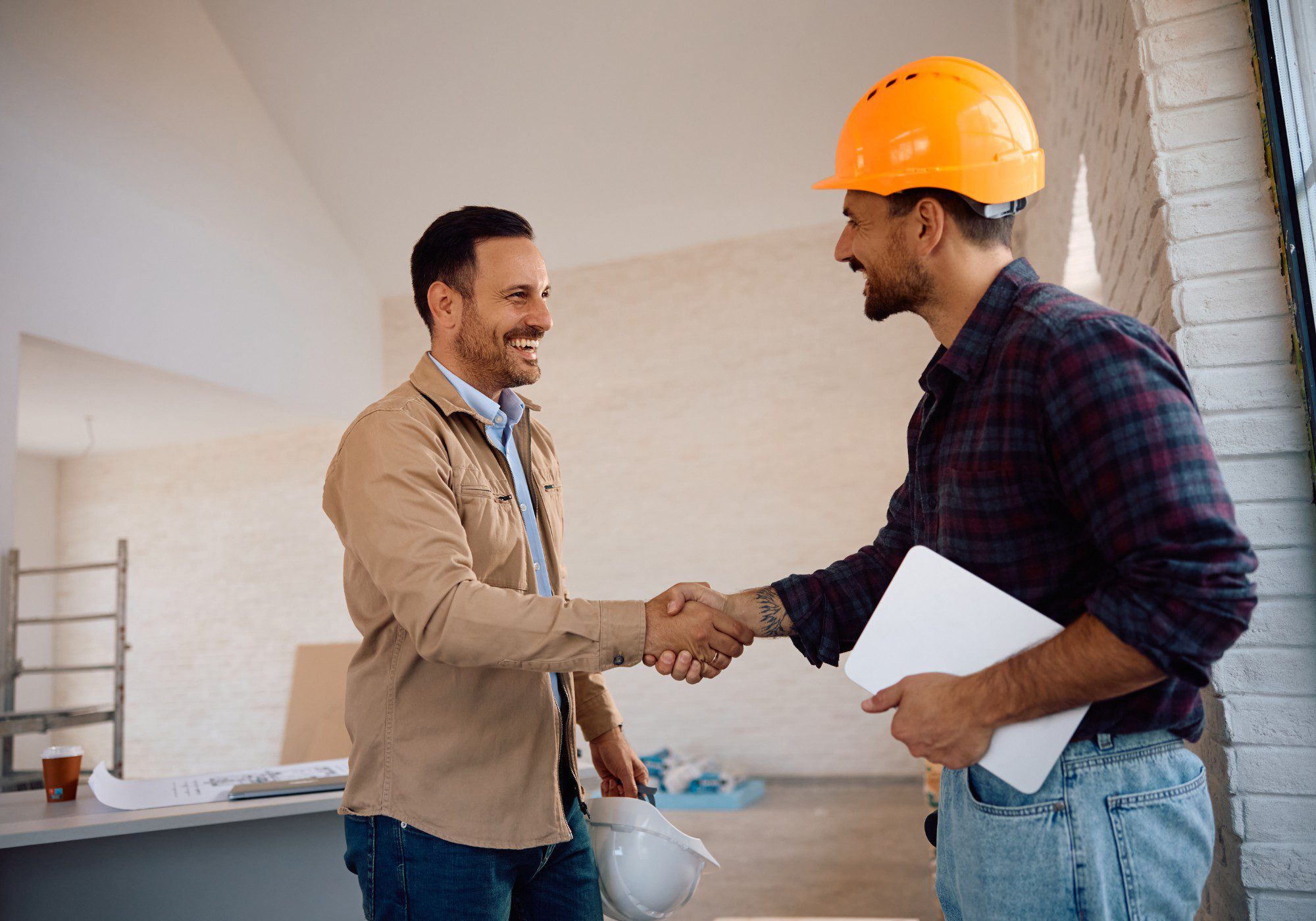 Two men shaking hands at construction site.